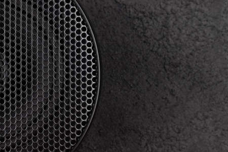Stylish car audio acoustic round speaker with waffle grill protector cover on dark black background closeup with copy space. Modern music textureの写真素材