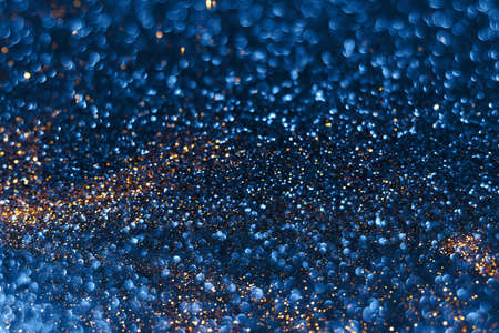 Blue and golden sparkling glitter bokeh background, christmas abstract defocused texture. Holiday lightsの写真素材