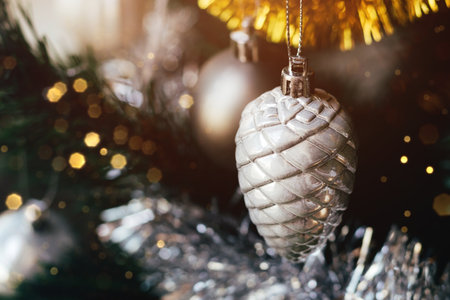 Silver gray toy cone on decorated Christmas tree with blurred lights bokeh. Holiday card with decorations for the New Years Eve. Selective focusの写真素材