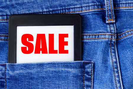 Sale sign on electronic book or tablet in the back pocket of blue denim jeans. Shopping conceptの写真素材