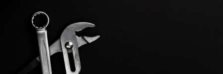 Steel closed end ring wrench and pliers on black background. Wide panoramic banner with copy spaceの写真素材