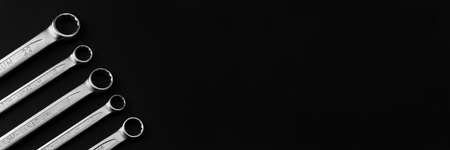 Steel closed end ring wrenches on black background. Wide panoramic banner with copy spaceの写真素材