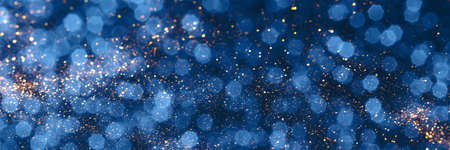 Blue and golden sparkling glitter bokeh background, christmas texture. Holiday lights. Abstract defocused header. Wide screen wallpaper. Panoramic web banner with copy space for designの写真素材