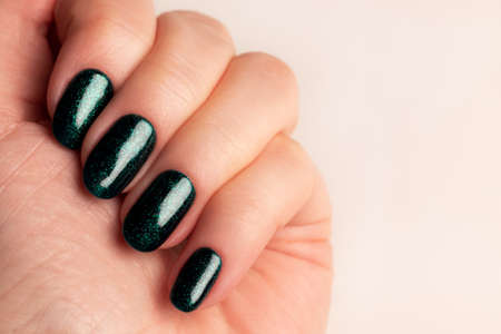 Female hand with beautiful manicure - green glittered nails. Nail care conceptの写真素材