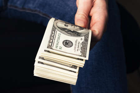 Male hand holding us hundred dollars banknotes. Man with american money closeupの写真素材