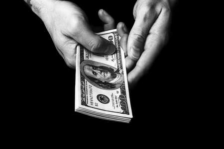 Male hands holding us hundred dollars banknotes. Man with american money closeup. Black and white photoの写真素材