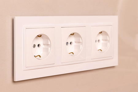 Group of white european electrical outlets on modern beige wall. Selective focus