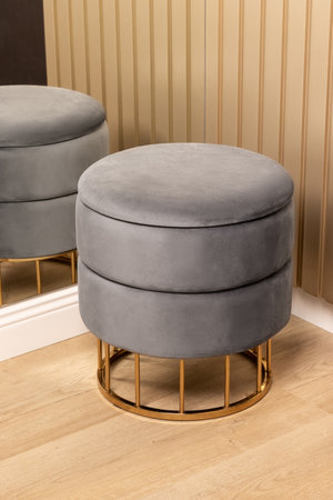 Gray pouf on golden metal base on wooden floor in corner of modern hallway near mirrorの写真素材