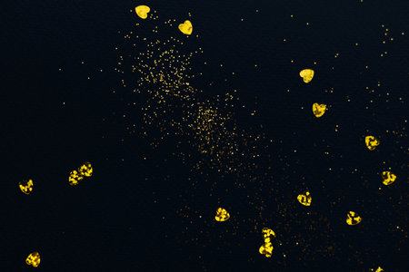 Dark blue background with golden glitter and hearts confettiの写真素材