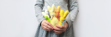 Little girl with colorful bright handmade Easter bunnies in her hands on gray background banner....
