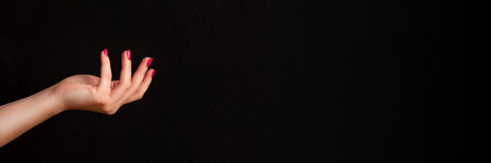 Female hand with beautiful manicure - viva magenta, pink nails on dark black background banner with copy space. Wide panoramic headerの写真素材