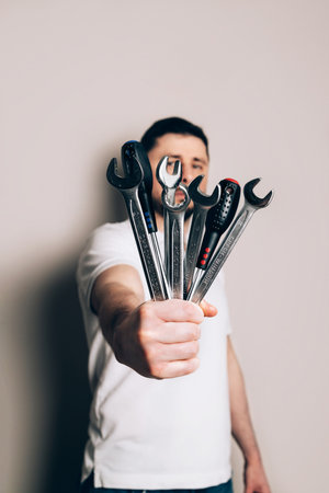 Man with bouquet of wrenches, spanners and screwdrivers in one hand. Fathers Day concept. Focus in the foregroundの写真素材