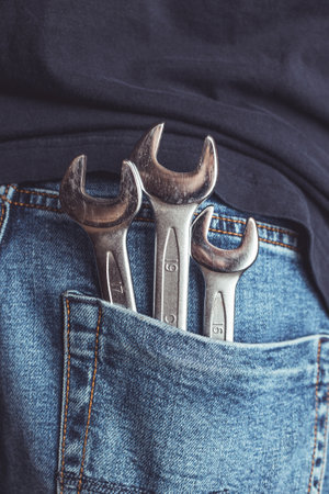 Man holding wrench in one hand. Side view. Ideal for industrial, mechanical, and DIY projectsの写真素材