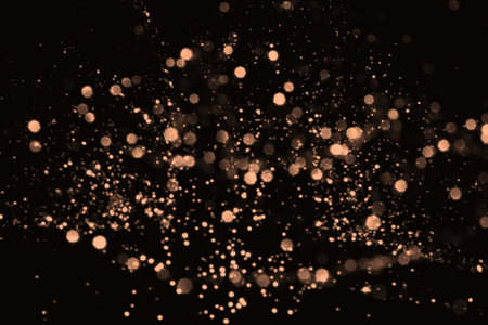 Peach fuzz blurred abstract bokeh lights on black background. Snowy shiny glitter sparkle stars for celebrateの写真素材