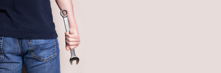 Man holding wrench banner. Back view. Ideal for industrial, mechanical, and DIY projects. Panoramic web header. Wide screen wallpaper.の写真素材