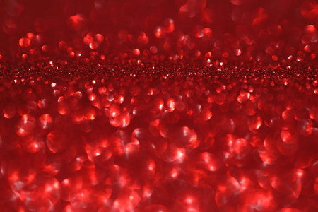Red glitter bokeh background with sparkling light, abstract defocused texture. Holiday lights.の写真素材