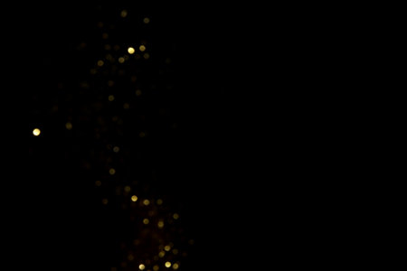 Golden blurred bokeh lights on black background. Glitter sparkle stars for celebrate. Overlay for your designの写真素材