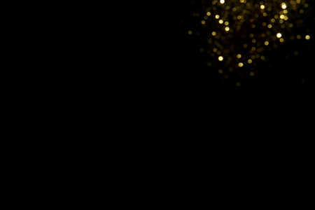 Golden blurred bokeh lights on black background. Glitter sparkle stars for celebrate. Overlay for your designの写真素材