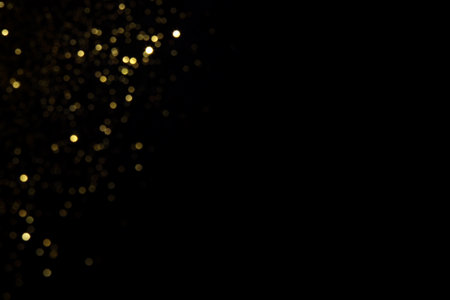 Golden blurred bokeh lights on black background. Glitter sparkle stars for celebrate. Overlay for your designの写真素材