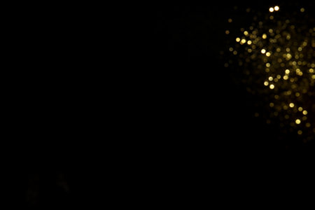 Golden blurred bokeh lights on black background. Glitter sparkle stars for celebrate. Overlay for your designの写真素材