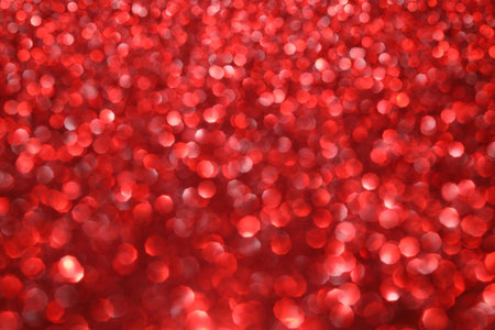 Red glitter bokeh background with sparkling light, abstract defocused texture. Holiday lights.の写真素材