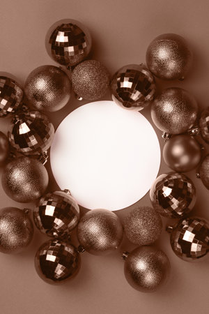 Brown, mocha mousse Christmas bauble balls decorations around white empty circle on brown background with copy space. Demonstrating color, trend 2025 yearの写真素材