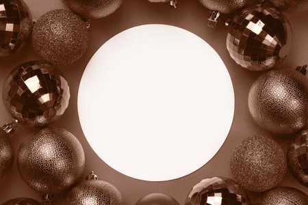 Brown, mocha mousse Christmas bauble balls decorations around white empty circle on brown background with copy space. Demonstrating color, trend 2025 yearの写真素材