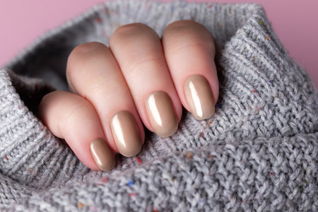 Female hand with beautiful trendy manicure - brown, mocha mousse nails. Nail care concept. Demonstrating color, trend 2025 year.の写真素材