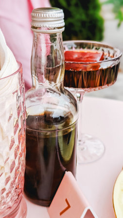 Brown glass bottle with cocktail glass on table, elegant dining setup. Soft lighting, stylish presentation.の写真素材