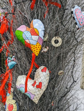 Colorful heart decorations made of fabric hanging on dry branches with red ribbons.の写真素材