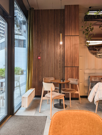 Cozy cafe interior featuring wooden wall, table, and chairs, bright ambiance.の写真素材