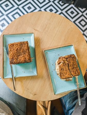 Two slices of dessert on plates with cutlery on wooden table. Top view dining setting.の写真素材