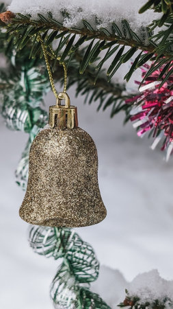 Gold glitter Christmas bell ornament, close-up. Winter holiday decoration. Snowy background.の写真素材