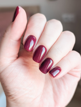 Elegant burgundy manicure with glossy finish on hand, well-groomed fingernails.の写真素材