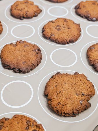Baked chocolate chip cookies cooling on baking sheet lined with silicone mat.の写真素材