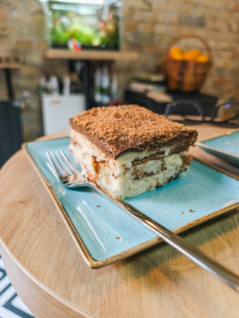 Delicious tiramisu dessert on blue plate, close view with fork on wooden table.の写真素材