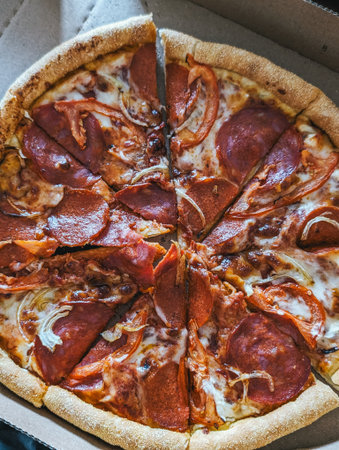 Sliced pepperoni pizza in delivery box, top view. Crispy crust with toppings.
