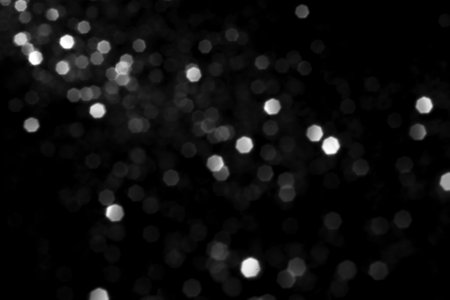 White gray blurred bokeh lights on black background. Glitter sparkle stars for celebrate. Overlay for your designの写真素材