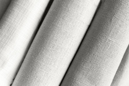 Diagonal textural background of cloud white natural linen fabric, rolled up. Demonstrating color, trend.の写真素材