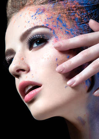Portrait of a beautiful Girl with red paint on her face. Photo shot in the Studio on a black...