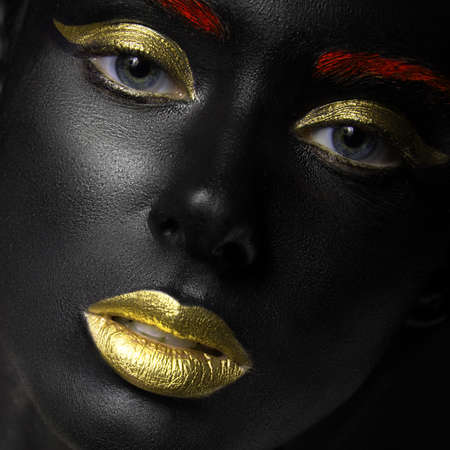 fashion portrait of a dark-skinned girl with color make-up.Beauty face. Picture taken in the studio on a black background.の写真素材
