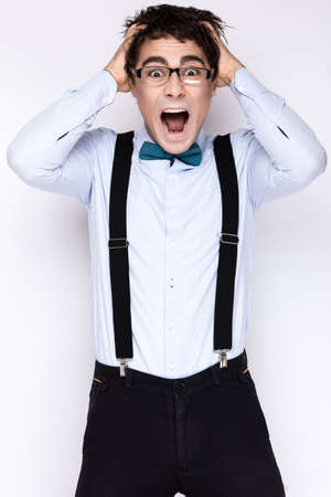 Handsome cheerful young man wearing glasses, a shirt with suspenders and a butterfly on his neck....