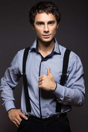 serious young man in a striped shirt with suspenders in business style. Picture taken in a studio on a dark background.の写真素材