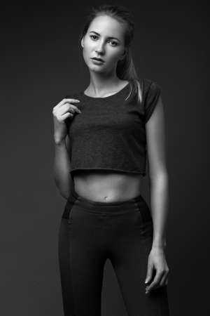 sexy fashion model with long hair, young European attractive, beautiful eyes, perfect skin is posing in studio for glamour vogue test photo shoot showing different poses. Picture taken in the studio on a gray background. Black and white photoの写真素材