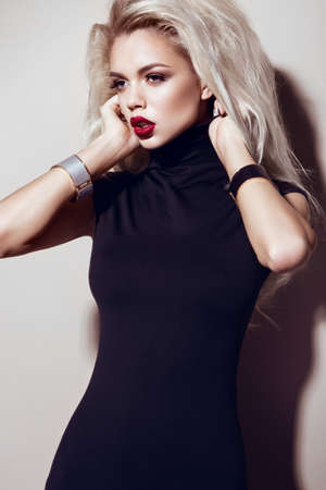 Beautiful sexy blonde girl with sensual lips, fashion hair, black dress and gold accessories. Beauty...