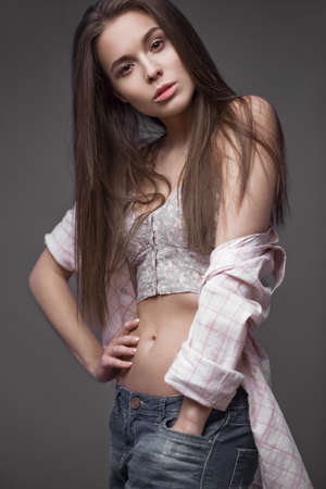 sexy fashion model with long hair, young European attractive, beautiful eyes, perfect skin is posing in studio for glamour vogue test photo shoot showing different poses. Picture taken in the studio on a gray background.の写真素材