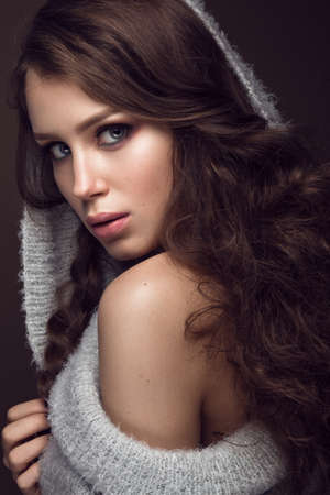 Beautiful young girl with gentle make-up in warm sweater and long straight hair. Beauty face. Studio portraitの写真素材