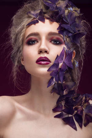 Creative fashionable image, the girl with a bright make-up and purple plant on the face. Picture taken in the studio.の写真素材