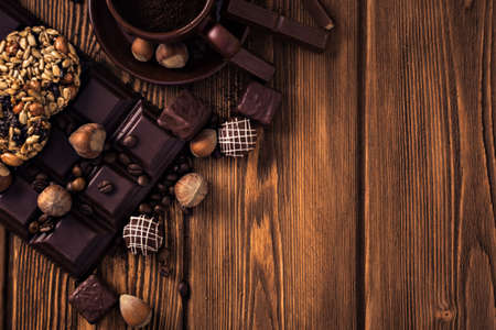 Roasted coffee beans, chocolate, candy, nuts, and a cup on the wooden background.の写真素材