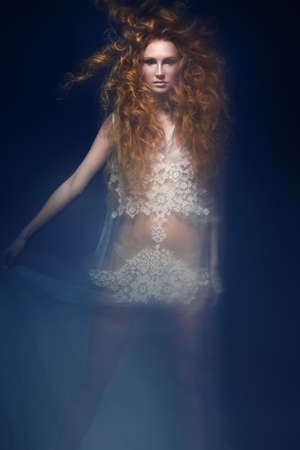 Beautiful fashionable red-haired girl in a transparent dress in mermaid image with creative...